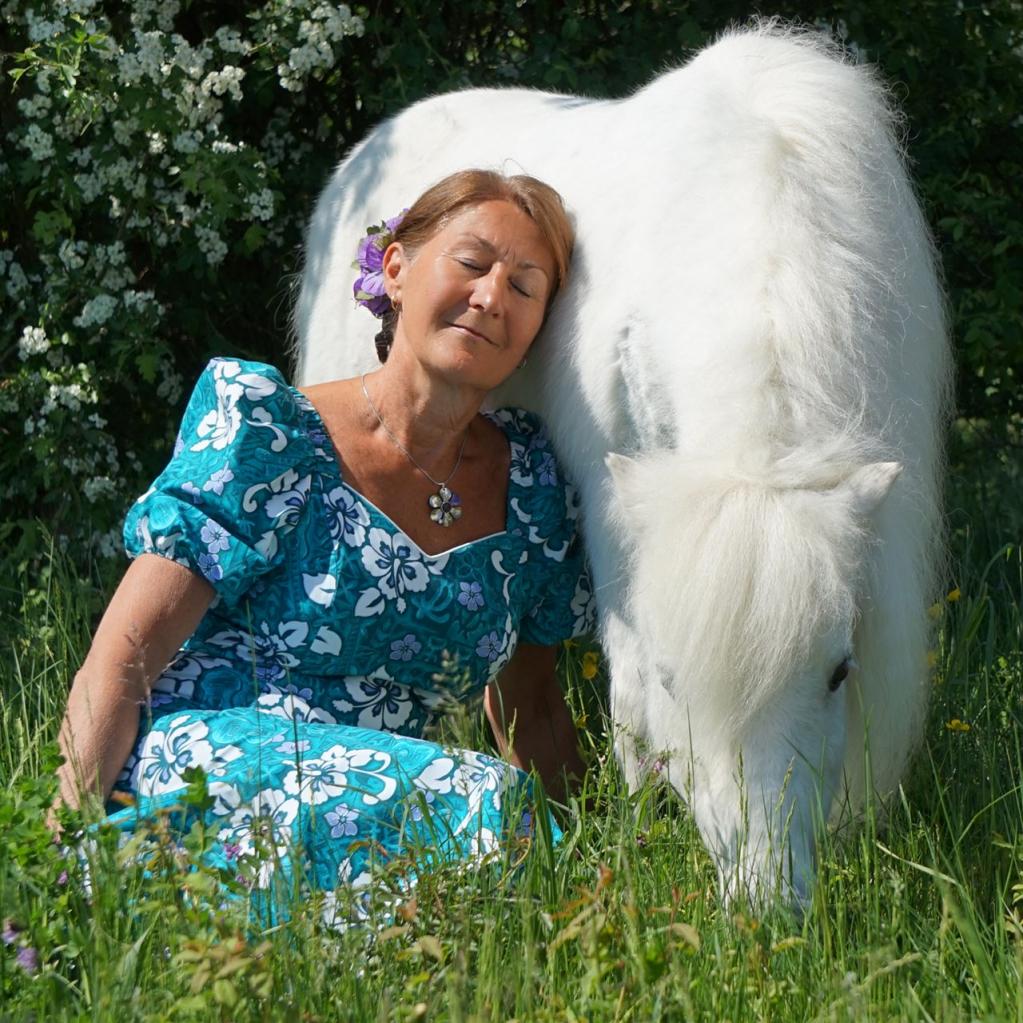 Elke Wedig mit einem weißen Pferd auf einer Wiese  